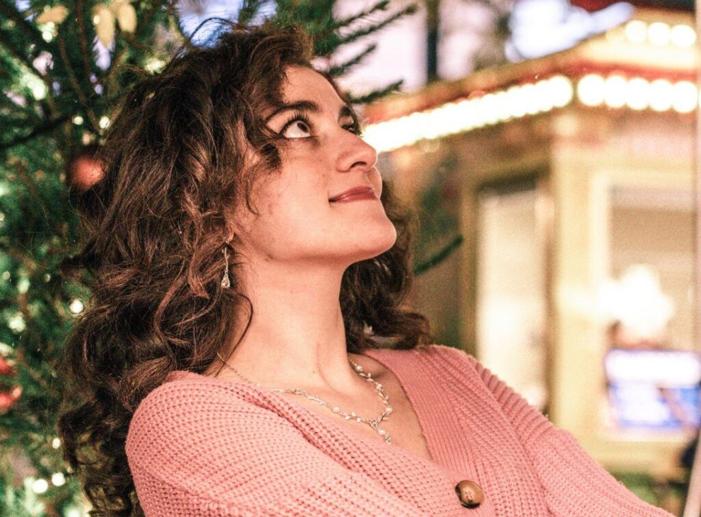 Girl smiling and looking up against Christmas tree background.
